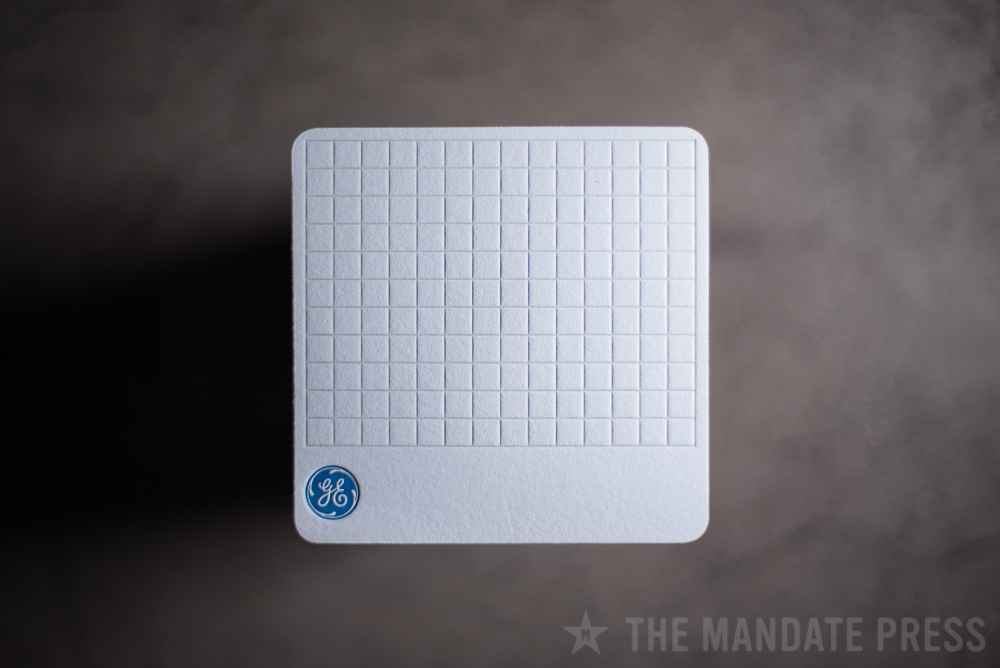letterpress printed square coaster for General Electric with blind deboss pattern and blue logo