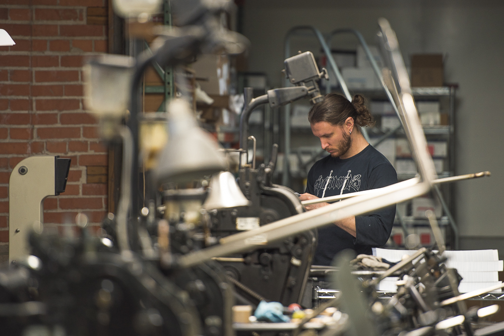 gabriel danilchik on phone surrounded by letterpress printing presses